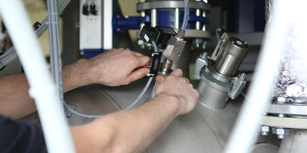 Hands adjusting components on an industrial cleaning machine, highlighting maintenance practices for improved machine uptime and reliability.